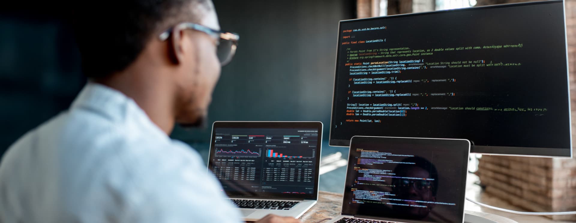 IT services professional monitoring coding screen with programming scripts and system operations.